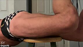 skinny bodybuilder stretches on stool in tight bikini briefs revealing muscular bulge and groin brace