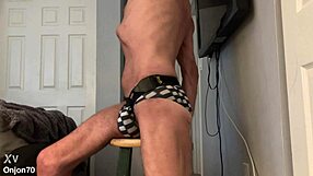 skinny bodybuilder stretches on stool in tight bikini briefs revealing muscular bulge and groin brace