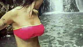 monika fox in pink top and yellow shorts walks through jungle and waterfalls